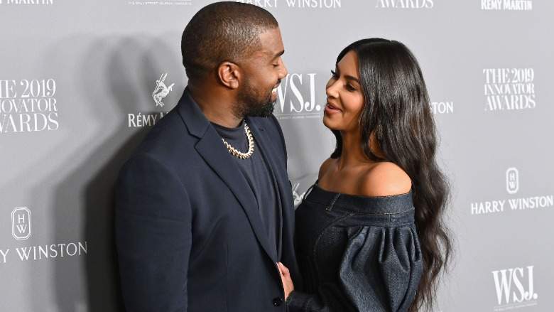 Kanye West looks at Kim Kardashian as she smiles and looks back.