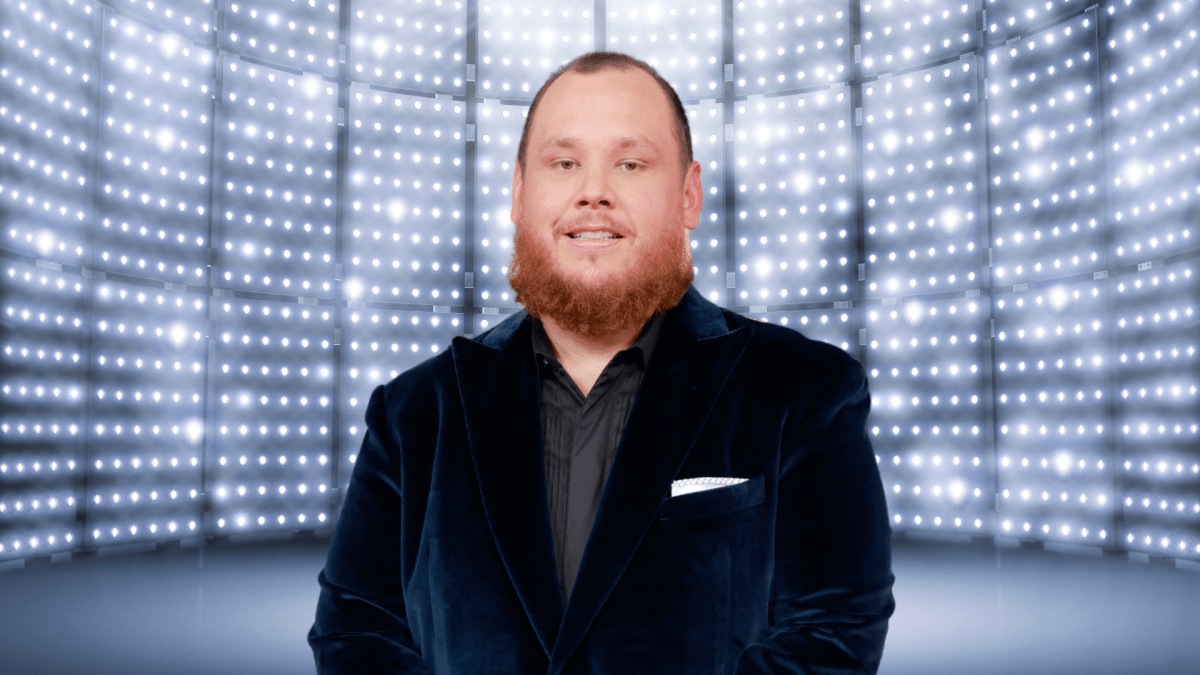 Luke Combs smiling in front of a bright background