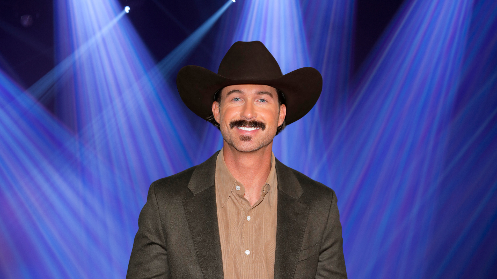 Riley Green wears a cowboy hat and smiles