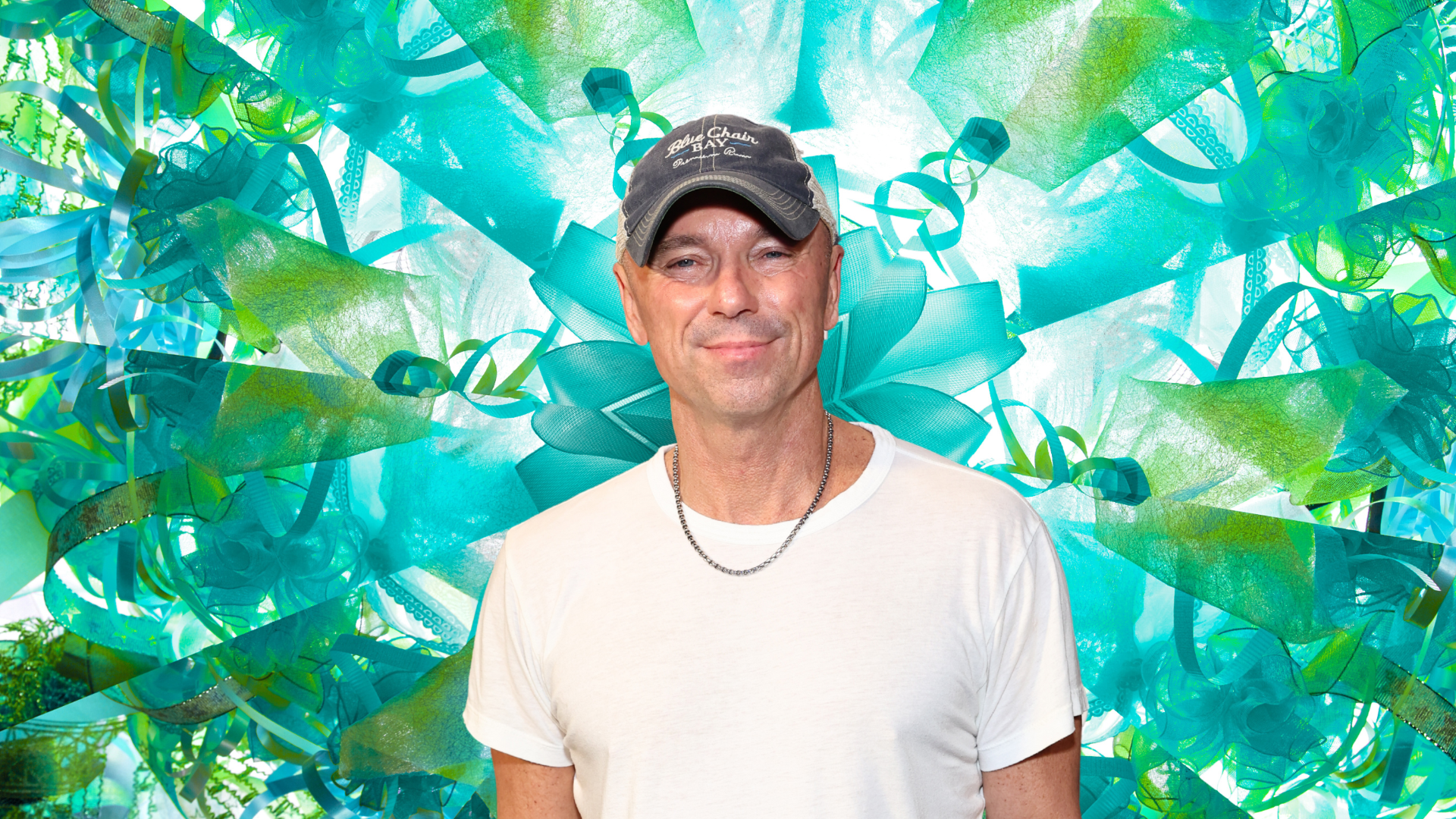 Kenny Chesney posing in front of a colorful background.