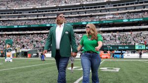 Former New York Jets player Nick Mangold walks on the field with his wife Jennifer Richmond as he is inducted into the Jets Ring of Honor during halftime of the game against the Cincinnati Bengals at MetLife Stadium on September 25, 2022