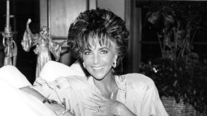 Elizabeth Taylor smiling while sitting on a sofa at her home in Los Angeles, California, April 1987