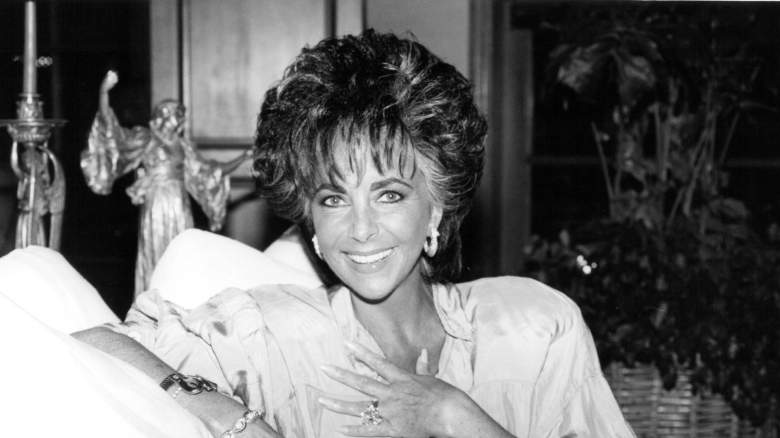 Elizabeth Taylor smiling while sitting on a sofa at her home in Los Angeles, California, April 1987
