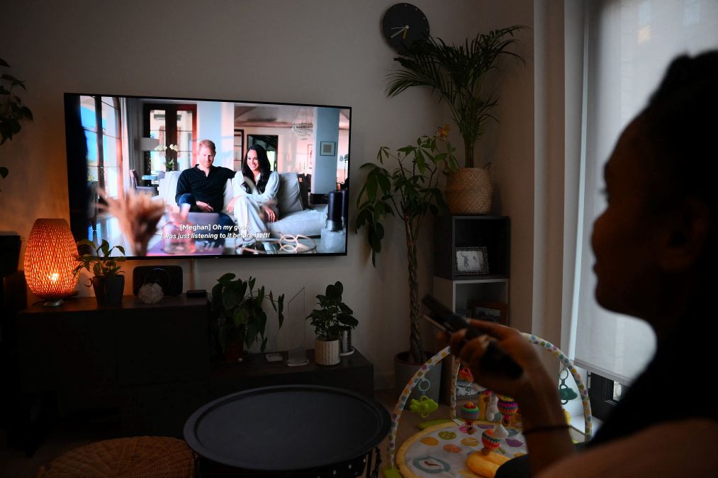  A woman poses as she watches an episode of the newly released Netflix docuseries "Harry and Meghan"