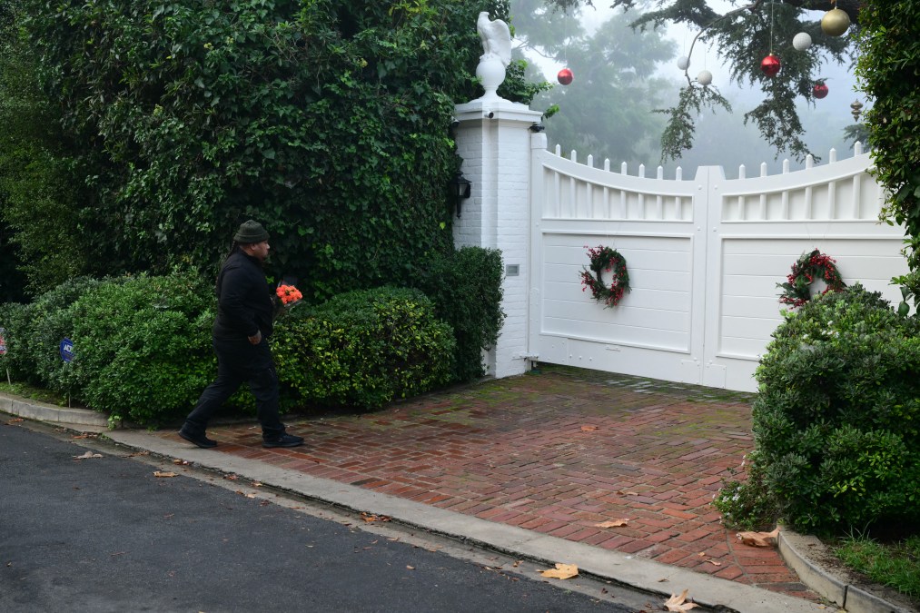 A man lays flowers at the entrance of US actor and director Rob Reiner's residence 