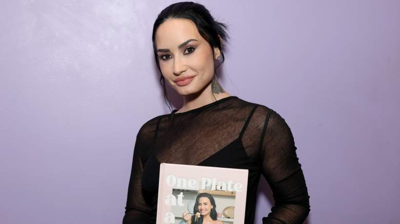 Demi lovato holds up a copy of her cookbook.
