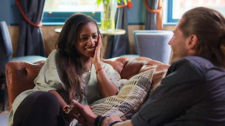Nicole Stevens holds hands with Benaiah Grunewald while sitting on a couch.